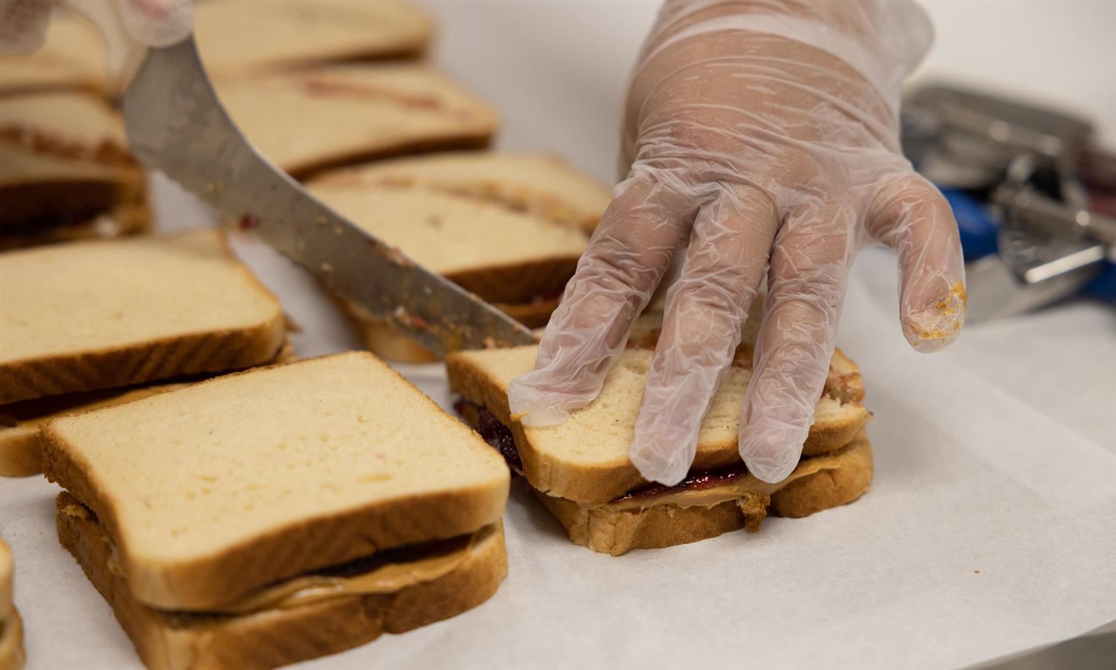 Cafeteria worker cuts peanut butter and jelly sandwiches